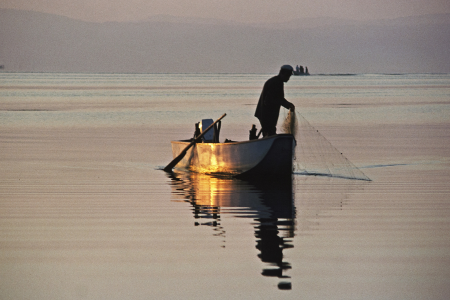 Pescador pescando con redes al amanecer
