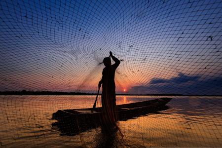 Pescador al amanecer tirando la red
